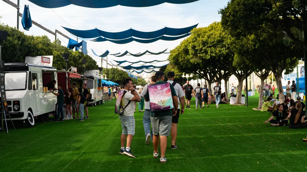 Avenida de food trucks cubierta con velas de sombra azules sobre cesped