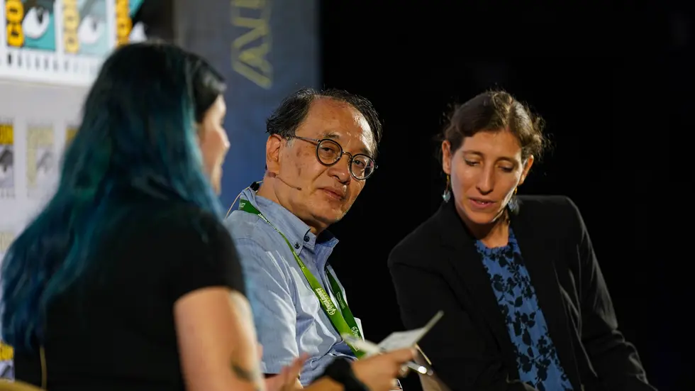 Autor japones entrevistado en el escenario con interprete al lado