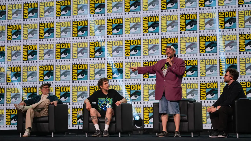 Kevin Smith de pie con un microfono en el panel de Mallrats junto a Jason Lee y Jason Mewes