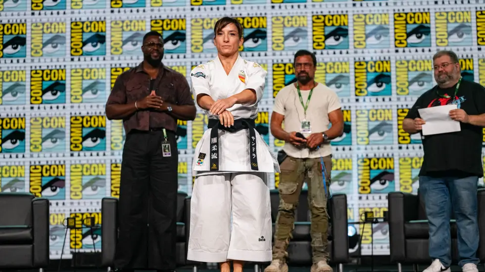 Sandra Sanchez con karategi en el escenario junto a Winston Duke y Manu Bennett