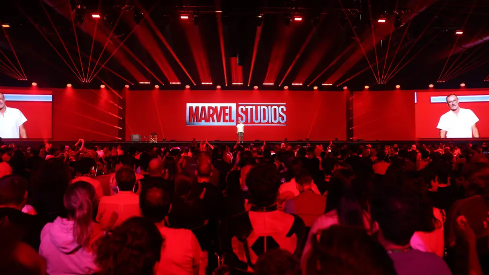 Sala llena iluminada de rojo con el logotipo de Marvel Studios en la pantalla gigante
